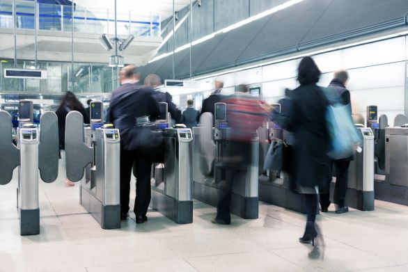 Blurred people entering through station ticket barrier