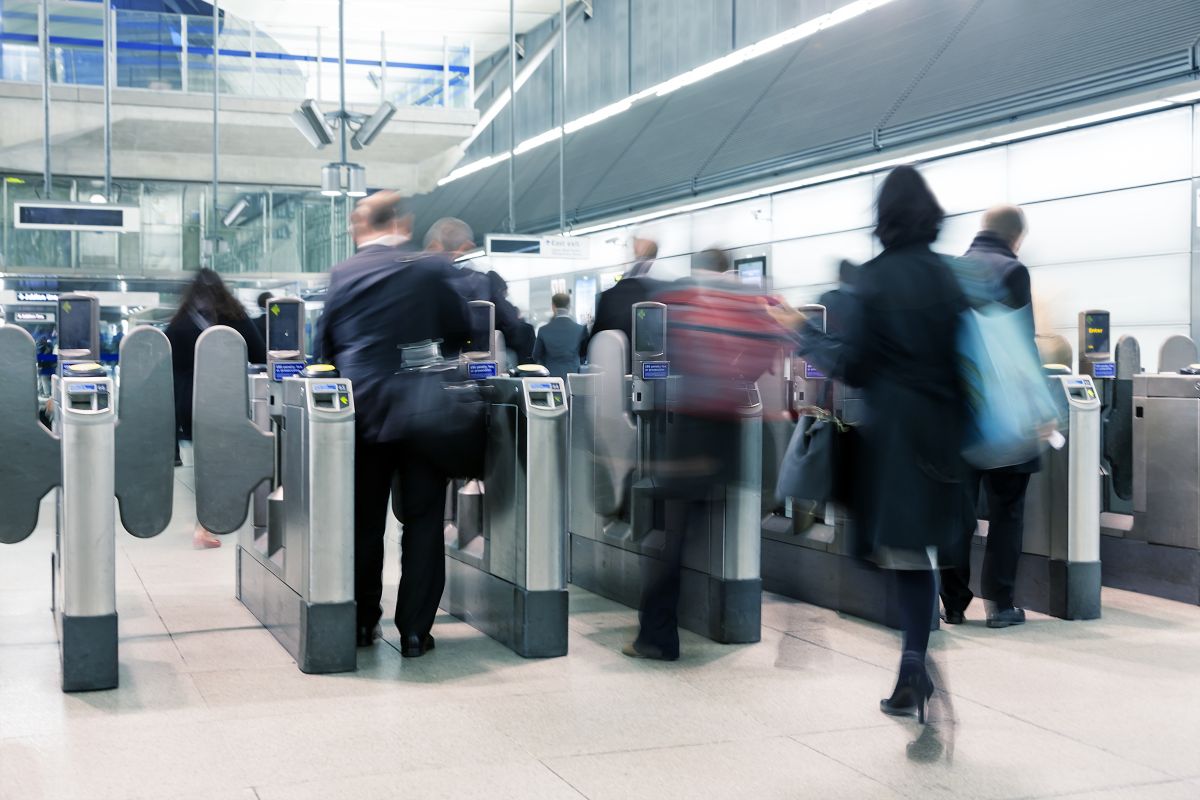 Blurred people entering through station ticket barrier